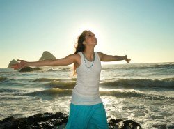 Woman on beach with open arms conveys a feeling of joy and freedom